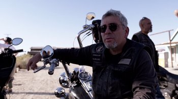 A man sitting on the back of a motorcycle wearing sunglasses
