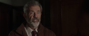 Movie still from “Dangerous” (2021), directed by David Hackl – An older man with a beard and a mustache wearing a suit and tie; Close Up shot, Low angle