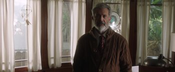 Movie still from “Dangerous” (2021), directed by David Hackl – An older man wearing a sweater and a tie; Medium shot, Over the shoulder angle