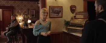 Movie still from “Dangerous” (2021), directed by David Hackl – A woman standing in front of an old fashioned radio; Medium shot, Over the shoulder angle