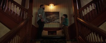Movie still from “Dangerous” (2021), directed by David Hackl – A man and a boy standing in front of a painting on the wall; Wide shot, Low angle