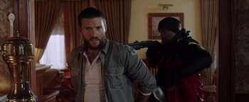 Movie still from “Dangerous” (2021), directed by David Hackl – A man with a gun in a room with another man; Medium shot, Over the shoulder angle