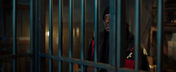 Movie still from “Dangerous” (2021), directed by David Hackl – A man standing behind bars in a jail cell; Medium shot, High angle