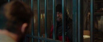 Movie still from “Dangerous” (2021), directed by David Hackl – A man in black jacket behind a metal fence; Medium shot, Over the shoulder angle