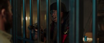 Movie still from “Dangerous” (2021), directed by David Hackl – A man holding a gun behind a metal fence; Medium shot, Low angle