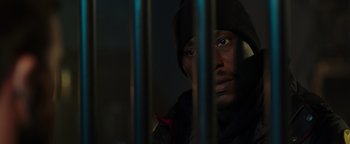 Movie still from “Dangerous” (2021), directed by David Hackl – A man in a black jacket behind a metal fence; Close Up shot, Low angle