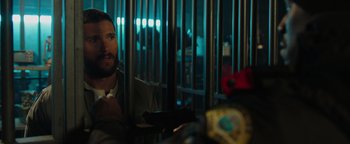 Movie still from “Dangerous” (2021), directed by David Hackl – A man sitting in front of a metal fence; Close Up shot, Over the shoulder angle