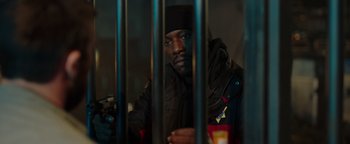 Movie still from “Dangerous” (2021), directed by David Hackl – A man in black jacket behind metal bars looking at the camera; Medium shot, Low angle
