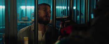 Movie still from “Dangerous” (2021), directed by David Hackl – A man holding a gun in front of another man in a jail cell; Close Up shot, Low angle