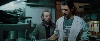 Movie still from “Dangerous” (2021), directed by David Hackl – Two men in a kitchen looking at a pan; Medium shot, Low angle