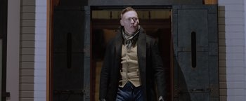 Movie still from “Dangerous” (2021), directed by David Hackl – A man in a black coat and a tie; Medium shot, Low angle