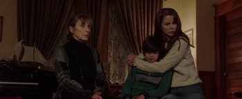 Movie still from “Dangerous” (2021), directed by David Hackl – Two women and a child sitting on a couch; Medium shot, Over the shoulder angle
