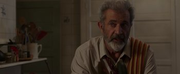 Movie still from “Dangerous” (2021), directed by David Hackl – An older man wearing a neck tie sitting in a room; Close Up shot, Over the shoulder angle