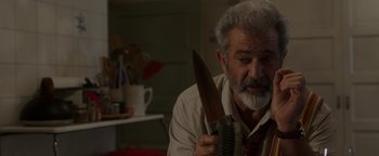 Movie still from “Dangerous” (2021), directed by David Hackl – An older man holding a large knife in his hand; Close Up shot, Over the shoulder angle