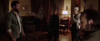 Movie still from “Dangerous” (2021), directed by David Hackl – A woman standing in a living room in a dark room; Wide shot, Over the shoulder angle