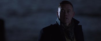 Movie still from “Dangerous” (2021), directed by David Hackl – A man wearing a black jacket and a scarf; Close Up shot, Low angle