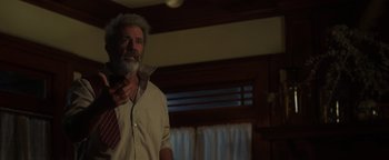 Movie still from “Dangerous” (2021), directed by David Hackl – An older man wearing a neck tie in a living room; Medium shot, Low angle