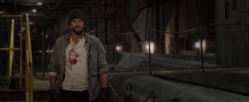 Movie still from “Dangerous” (2021), directed by David Hackl – A man with a beard and a hat standing next to a boat; Medium shot, Over the shoulder angle