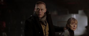 Movie still from “Dangerous” (2021), directed by David Hackl – A man wearing a black coat and a yellow shirt; Close Up shot, Over the shoulder angle