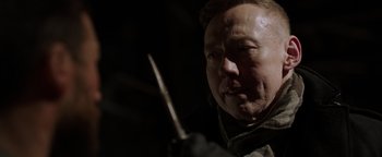 Movie still from “Dangerous” (2021), directed by David Hackl – A man holding a wooden stick in his hand; Close Up shot, Over the shoulder angle