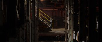 Movie still from “Dangerous” (2021), directed by David Hackl – A man standing next to a yellow and yellow stair railing; Wide shot, Low angle
