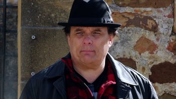 Movie still from “Dark Light” (2021), directed by Damian Chapa – A person wearing a hat and a jacket; Close Up shot, Low angle