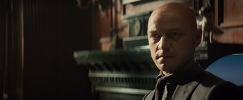 Movie still from “Dark Phoenix” (2019), directed by Simon Kinberg – A bald man wearing a neck tie in front of a fireplace; Close Up shot, Low angle