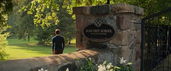 Movie still from “Dark Phoenix” (2019), directed by Simon Kinberg – A man standing in front of a sign for jean grey school for gifted and talented students; Extreme Wide shot, Over the shoulder angle