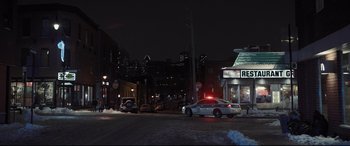Movie still from “To Catch a Killer” (2023), directed by Damián Szifron – A police car parked on the side of the road at night; Extreme Wide shot, High angle