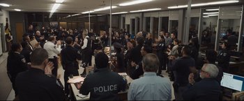Movie still from “To Catch a Killer” (2023), directed by Damián Szifron – A large group of people gathered in a room; Wide shot, High angle