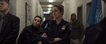 Movie still from “To Catch a Killer” (2023), directed by Damián Szifron – A woman in a police uniform standing next to other people; Medium shot, Over the shoulder angle