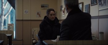 Movie still from “To Catch a Killer” (2023), directed by Damián Szifron – A woman sitting at a table talking to a man; Medium shot, Over the shoulder angle