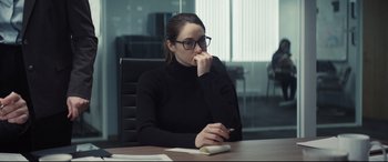 Movie still from “To Catch a Killer” (2023), directed by Damián Szifron – A woman sitting at a table with a cell phone in her hand; Medium shot, Over the shoulder angle