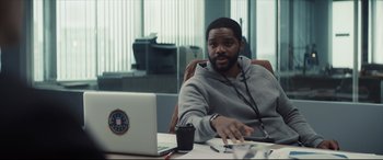 Movie still from “To Catch a Killer” (2023), directed by Damián Szifron – A man sitting in front of a laptop computer in an office; Medium shot, Over the shoulder angle