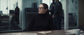 Movie still from “To Catch a Killer” (2023), directed by Damián Szifron – A woman sitting at a table in front of a book; Medium shot, Over the shoulder angle