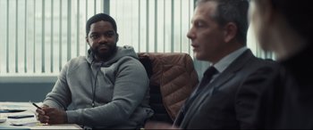 Movie still from “To Catch a Killer” (2023), directed by Damián Szifron – Two men sitting on a couch in a room; Medium shot, Over the shoulder angle