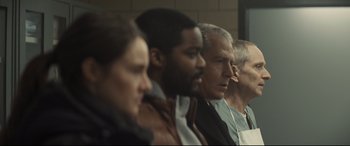 Movie still from “To Catch a Killer” (2023), directed by Damián Szifron – A group of people sitting in a room; Medium shot, Over the shoulder angle