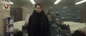 Movie still from “To Catch a Killer” (2023), directed by Damián Szifron – A woman standing in a room next to a man; Medium shot, Over the shoulder angle