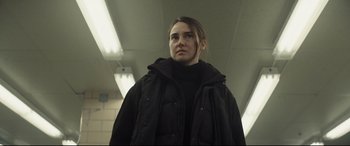 Movie still from “To Catch a Killer” (2023), directed by Damián Szifron – A woman wearing a black jacket standing in a hallway; Medium shot, Low angle