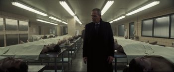 Movie still from “To Catch a Killer” (2023), directed by Damián Szifron – A man standing in front of a group of dead bodies; Wide shot, Low angle