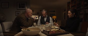 Movie still from “To Catch a Killer” (2023), directed by Damián Szifron – Three men sitting at a dinner table with food; Medium shot, Over the shoulder angle