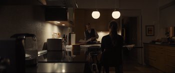 Movie still from “To Catch a Killer” (2023), directed by Damián Szifron – A man and a woman are sitting at a kitchen table; Medium shot, Over the shoulder angle