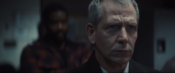 Movie still from “To Catch a Killer” (2023), directed by Damián Szifron – A person wearing a suit and tie; Close Up shot, Over the shoulder angle