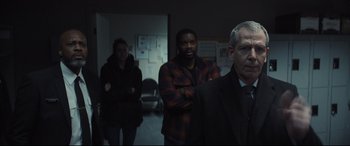 Movie still from “To Catch a Killer” (2023), directed by Damián Szifron – A group of people standing in a dark room; Medium shot, Over the shoulder angle