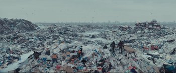 Movie still from “To Catch a Killer” (2023), directed by Damián Szifron – A large amount of trash is in the middle of a field; Extreme Wide shot, High angle