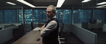 Movie still from “To Catch a Killer” (2023), directed by Damián Szifron – A man standing in an office with his arms crossed; Medium shot, Over the shoulder angle