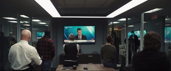 Movie still from “To Catch a Killer” (2023), directed by Damián Szifron – A group of people sitting at a table watching television; Medium shot, Over the shoulder angle