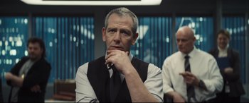 Movie still from “To Catch a Killer” (2023), directed by Damián Szifron – A man in a vest and tie sitting in front of a window; Close Up shot, Over the shoulder angle