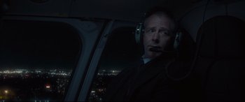 Movie still from “To Catch a Killer” (2023), directed by Damián Szifron – A man in a helicopter at night looking out of the window; Close Up shot, Over the shoulder angle