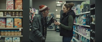 Movie still from “To Catch a Killer” (2023), directed by Damián Szifron – An old man and a young woman talking in a store; Medium shot, Over the shoulder angle
